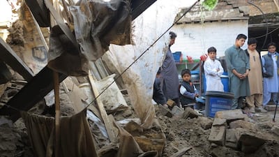 People look at a house damaged by massive earthquake in Mingora, Swat valley, Pakistan. Naveed Ali / AP Photo