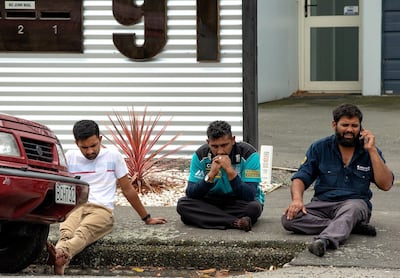 Grieving members of the public sit on a curb following the massacre. EPA