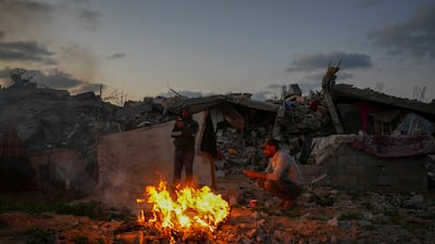 Palestinians sit by a fire next to their tent in an area littered with rubble from buildings demolished during the Israeli army's ground and air offensive against Hamas in Gaza City. AP