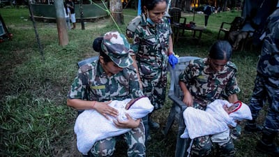 Nepali military personnel comfort twin infants during rescue operations in the aftermath of deadly flash floods. AFP