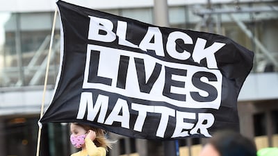 A young girl holds a flag reading 'Black Lives Matter' as protesters march through downtown Minneapolis on the first day of opening statements for the murder trial of former Minneapolis police officer Derek Chauvin who was charged in the death of George Floyd. EPA