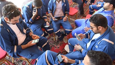 Kuwait Oil and Petrochemical Industries Union workers sit with their cellphones on the first day of an official strike over public sector pay reforms, in Ahmadi, Kuwait April 17, 2016. Stephanie McGehee/Reuters