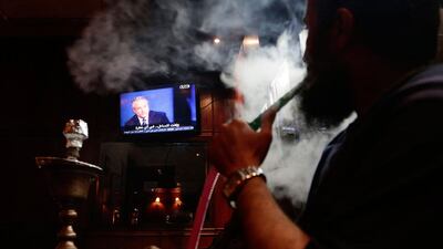 A man smokes shisha as he watches Jon Stewart on a TV screen at a coffee shop, in Cairo. Jon Stewart has appeared on Egypt's top satirical TV program, modeled after his own program 'The Daily Show'. Stewart was brought to the set wearing a black hood and introduced by host Bassem Youssef as a captured foreign spy. Hassan Ammar)? / AP Photo