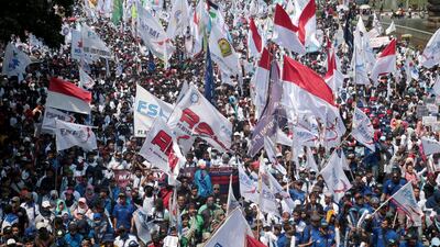 Indonesians wave flags as they march along a road towards the Presidential Palace during a May Day rally in Jakarta, Indonesia. Bagus Indahono / EPA