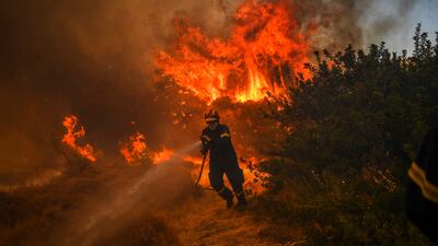 A firefighter tackles a blaze in the village of Markati, near Athens. More wildfires broke out on Monday in Greece, parts of which have been burning for more than two weeks, fanned by strong winds.