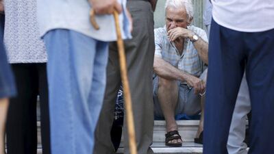 A pensioner sits in front of a National Bank branch as he waits to receive part of his pension in Athens. Christian Hartmann / Reuters