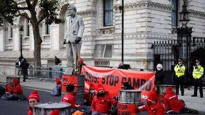 Greenpeace activists surround the statue of Boris Johnson as they stage their sit-in protest. AFP