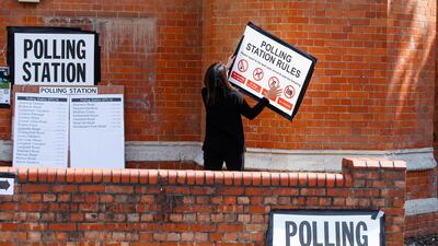 A woman attaches a sign on the wall of a polling station in London. Reuters