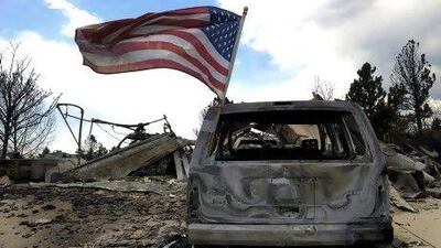 A US flag flies on a burnt car after fire ravaged 350 homes in a neighbourhood in Colorado Springs, Colorado last week.