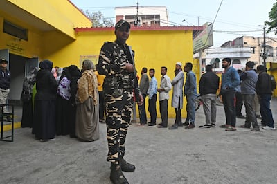 A security officer stands guard as people wait in a queue to cast their their votes for the state elections in Bhopal, Madhya Pradesh. AP Photo