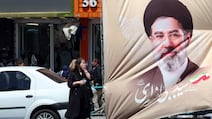 People wait for a taxi in front of a poster of Iranian supreme leader Ayatollah Mojtaba Khamenei in Tehran, as uncertainty persists under an indefinite ceasefire. EPA