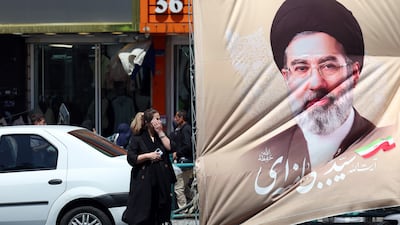 People wait for a taxi in front of a poster of Iranian supreme leader Ayatollah Mojtaba Khamenei in Tehran, as uncertainty persists under an indefinite ceasefire. EPA