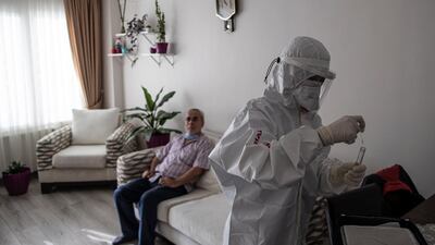 Tugce Atak (right), health worker of Memorial hospital wearing full protective suits collects a swab sample during a Covid-19 test service at home in Istanbul, Turkey. EPA