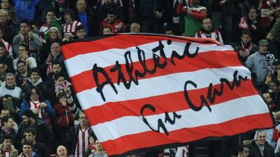 Athletic Bilbao's players celebrate after scoring as a supporter waves the club's flag reading "we are Athletic" during a Uefa Champions League Group H match against Bate Borisov at the San Mames stadium in Bilbao on December 10, 2014. Ander Gillena / AFP