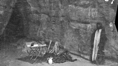 Shakespear’s camping gear and Arab figure by rock face and cave, probably in mountains in vicinity of Wadi Iram/Yatun Aqabah.