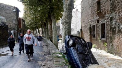 People walk past a submerged car. EPA