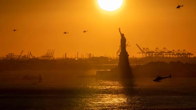 Helicopters fly in the distance as the sun sets behind the Statue of Liberty in New York. AFP