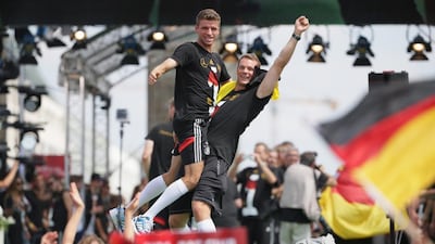 Thomas Muller, left, and Neuer cheer and celebrate on stage during the welcome reception. Michael Kappeler / EPA