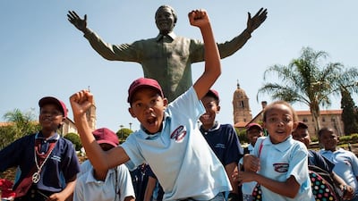 South African children cheer and pose beside the Nelson Mandela statue at the Union Buildings in Pretoria. Stefan Heunis / AFP Photo