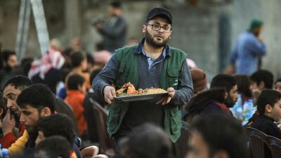 A volunteer serves a meal to displaced Syrians during a community iftar, donated by the independent civil society organisation Ulfah, with support from Malaysia, near the city of Al Bab. AFP
