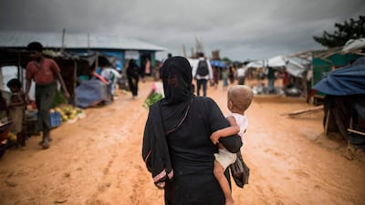 A Rohingya Muslim refugee carries a child through Kutupalong refugee camp in the Bangladeshi district of Ukhia on September 28, 2017.