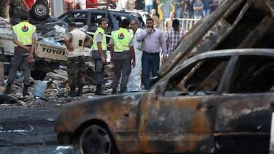 A Hizbollah security man, right, speaks on his radio as civil defence workers check the site of a car bomb explosion in a southern suburb of Beirut on Thursday..