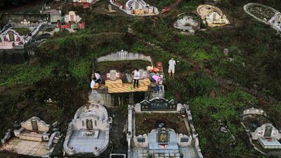 A Chinese-Malaysian family, with offerings of food and paper money, praying at the grave of an ancestor on the eve of the Qingming festival, known as ‘Tomb Sweeping Day’, in Karak, Malaysia. AFP