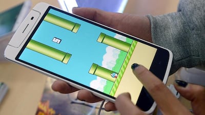 An employee plays the game Flappy Bird at a smartphone store in Hanoi. The Vietnamese developer behind the smash-hit free game Flappy Bird has pulled his creation from online stores after announcing that its runaway success had ruined his "simple life". Nam Hoang Dinh Ham / AFP photo