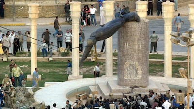 Iraqis watch a statue of Saddam Hussein being pulled down in Baghdad on April 9, 2003. AFP