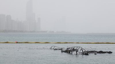Charred remains of a houseboat float around the Adnoc station yesterday Mona Al Marzooqi / The National