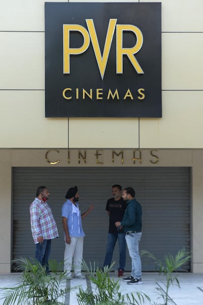People stand outside a closed cinema in Amritsar on October 15, 2020. AFP