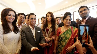 Stars Manju Warrier, left, and Aishwarya Rai Bachchan, centre, stand either side of T S Kalyanaraman, chairman and managing director of Kalyan Jewellers, at yesterday’s opening of the company’s jewellery showroom in Al Qusais, Dubai. Christopher Pike / The National