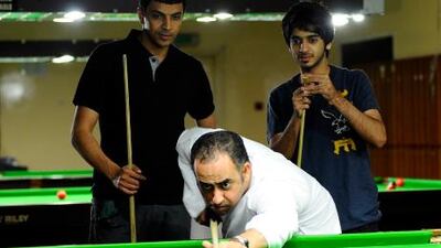 Mohammed Al Joker pratices at Dubai Snooker Club as his World Cup teammate Mohamed Shehab, left, and UAE's rising star Khalid Kamali look on.