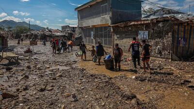 Residents carry salvaged belongings along a road covered in mud and debris in Rodriguez, Rizal. EPA