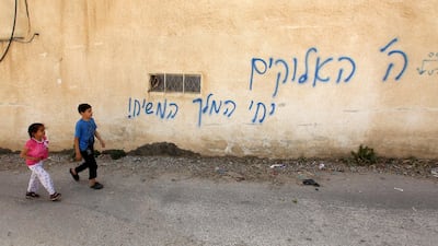 Palestinian children walk past a graffiti sprayed on a wall by suspected Jewish extremists reading in Hebrew "The Lord is gone, long life to the king, the Messiah", at Al Sawiyah village near the West Bank city of Nablus, 17 April 2018. Alaa Badarneh / EPA