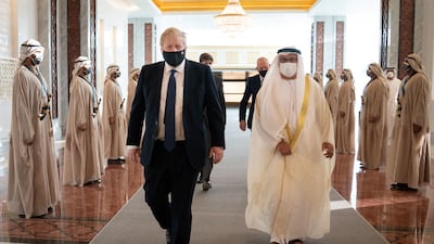 Mr Johnson inspects a guard of honour as he walks with Anwar Gargash, diplomatic adviser to the UAE President. Reuters