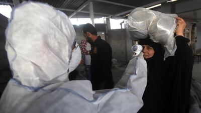 A member of a medical team checks the body temperature of an Iraqi woman upon her arrival at the Shalamcheh border crossing with Iran on Thursday. EPA