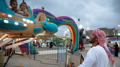 A father watches his children ride the Spaceship at the Eid fair at the Fujairah Exhibition Centre in Fujairah City on September 8, 2016. Victor Besa for The National