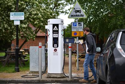 A man charges his vehicle at a recharging point at Maidstone Services on the M20 motorway, south-east of London, on May 24, 2021. Energy regulator Ofgem has announced on Monday it is investing £300 million to expand the UK's electric vehicle charging network and invest in over 200 low carbon projects. / AFP / Ben STANSALL
