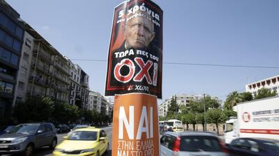 A poster depicting German finance minister Wolfgang Schaeuble with the message ’For five years he is drinking your blood, now tell him NO’, hangs above another one reading ‘Yes to Greece, Yes to Euro’ on a lamp post in Athens on July 3, 2015. Thanassis Stavrakis / AP Photo