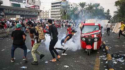 An Iraqi protester runs with a tear gas canister amidst clashes with security forces in the capital Baghdad between Tahrir Square and al-Jumhuriya bridge which connects to the high-security Green Zone, hosting government offices and foreign embassies during the ongoing anti-government protests. AFP