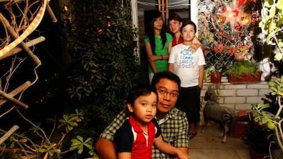 Bal Junio with his son Alexander, and his wife Evangeline with Angelika and Julian, outside their home in Abu Dhabi as a parol, top right, lights up the yard.