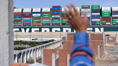 A man waves at the Panama-flagged MV 'Ever Given' container ship as it is tugged in Egypt's Suez Canal after it was fully dislodged from the banks, near Suez city. AFP