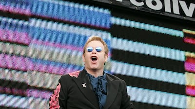 Elton John, wearing a black coat with pink, feathered pattern over a navy satin shirt and burnt orange wide-legged trousers, performs at the Live 8 London concert in Hyde Park, London on July 2, 2005. Getty Images