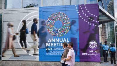 People walk past a poster announcing the annual meetings of The World Bank and International Monetary Fund (IMF) outside the IMF headquarters in Washington on October 7. The IMF extended debt relief to 24 low-income countries. AFP