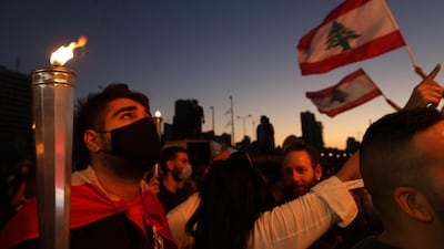 People hold Lebanese flags and lit candles to mark the first anniversary of anti-government protests. Getty Images