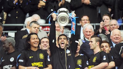 Jordi Gomez, centre, lifts the FA Cup trophy after helping Wigan Athletic defeat Manchester City in the 2013 final. Andy Rain / EPA