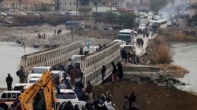 Civilians and military personnel gather at a crossing over the Euphrates at Deir Ezzor, eastern Syria, after the SDF withdrew. Reuters