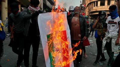 Iraqi anti-government protesters burn an Iranian flag during ongoing protests in Baghdad, Iraq. AP Photo