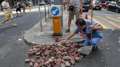 A man cleans broken pavement from a road, a day after violent clashes between protesters and police, in Hong Kong, China, 02 October 2019. EPA